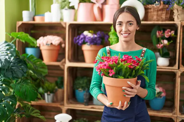 Joven Mujer Hispana Trabajando Floristería Sosteniendo Planta Con Aspecto Positivo — Foto de Stock