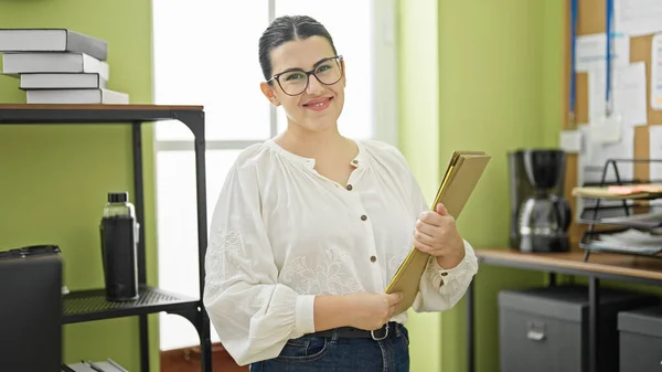 若い美しいヒスパニック系女性ビジネスワーカー オフィスで自信を持ってフォルダを保持する笑顔 — ストック写真