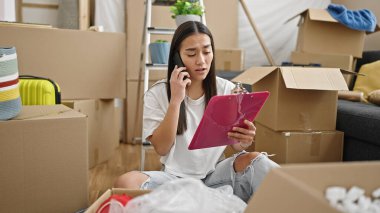 Genç, güzel İspanyol bir kadın yeni evdeki akıllı telefon okuma dokümanlarını tartışarak karton kutuları açıyor.