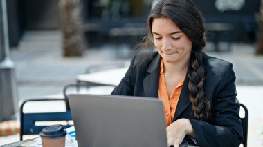 Genç, güzel İspanyol iş kadını. Kahve dükkanının terasında dizüstü bilgisayar kullanıyor.