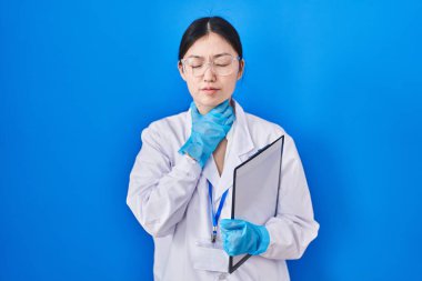 Laboratuvarda çalışan Çinli genç bir kadın ağrılı bir boyuna dokunuyor. Grip, mantar ve enfeksiyon yüzünden boğaz ağrısı çekiyor. 