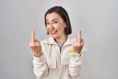Middle age hispanic woman standing over isolated background showing middle finger doing fuck you bad expression, provocation and rude attitude. screaming excited 