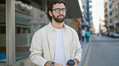 Genç İspanyol adam sokakta kahve içiyor.