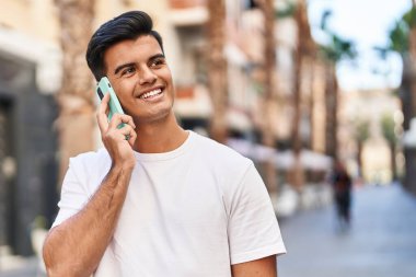 Genç İspanyol adam gülümsüyor. Kendine güveniyor. Sokakta akıllı telefondan konuşuyor.