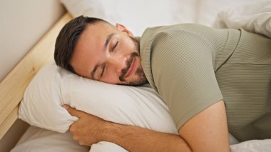 Genç İspanyol adam yatakta uzanıp yatak odasında uyuyor.