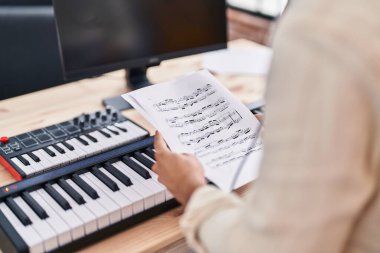 Genç İspanyol müzisyen müzik stüdyosunda nota tutuyor.