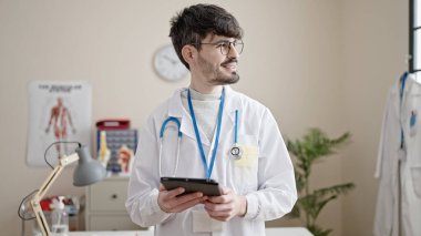 Genç İspanyol doktor klinikte dokunmatik ped kullanıyor.