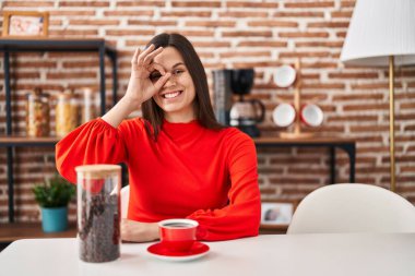 Genç İspanyol kadın evde kahve içiyor gülümsüyor mutlu bir şekilde el pençe divan duruyor. 