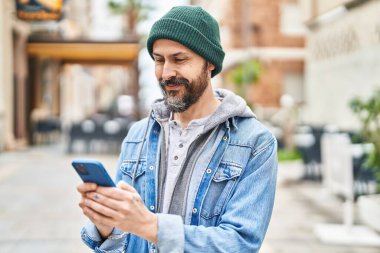 Sokakta akıllı telefon kullanarak kendine güvenen genç kel adam.