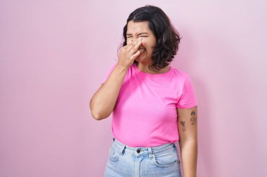 Pembe arka planda duran genç İspanyol kadın pis ve iğrenç bir koku alıyor. Nefesini burnunda tutuyor. Kötü kokuyor. 