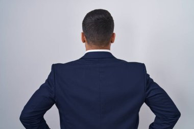 Yakışıklı İspanyol takım elbiseli ve kravatlı adam kolları vücudunda geriye doğru bakıyor. 