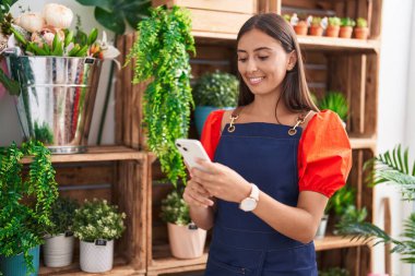 Çiçekçiye akıllı telefon kullanarak gülümseyen güzel İspanyol kadın.