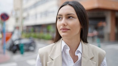 Young beautiful hispanic woman smiling confident looking to the side at street