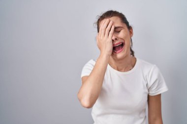 Güzel esmer kadın izole edilmiş arka planda duruyor. Yarı yüzünü, göz ve ağzını eliyle kapatmaktan yoruluyor. Yüzüm acıyor.. 