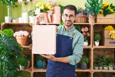 Çiçekçide çalışan yakışıklı İspanyol adam yüzünde ciddi bir ifadeyle rahatlamış. Basit ve doğal bir şekilde kameraya bakıyorsun.. 