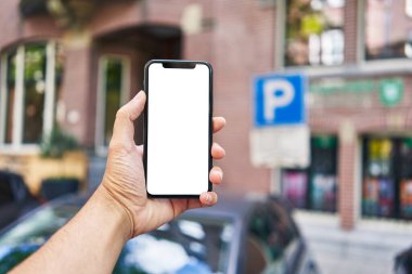 Akıllı telefonu tutan adam park yerinde beyaz ekranı gösteriyor.
