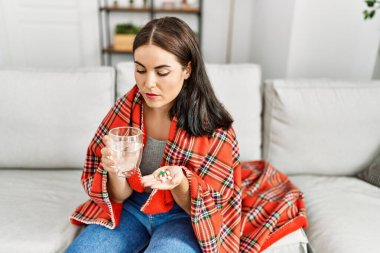 Evdeki kanepede oturup hap alan genç, güzel İspanyol kadın.