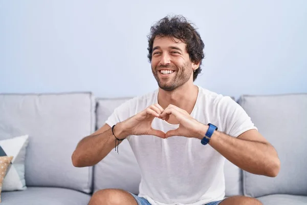 Young Hispanic Man Doing Heart Gesture Sitting Sofa Home — Foto Stock
