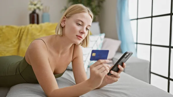 Ung Blond Kvinna Shopping Med Smartphone Och Kreditkort Ligger Soffan — Stockfoto