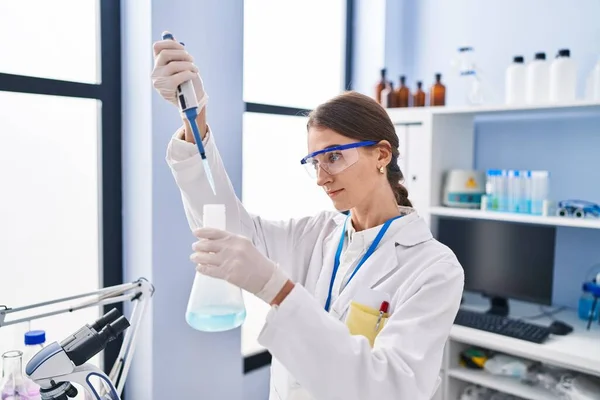 实验室里年轻的高加索女科学家把液体倒在试管上 — 图库照片