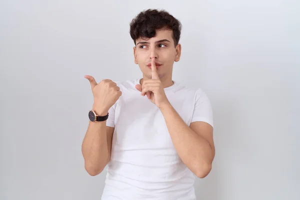 カジュアルな白いTシャツを着ている若い非バイナリ男性は 手を横に指で指で静かにするように頼みます 沈黙と秘密の概念 — ストック写真