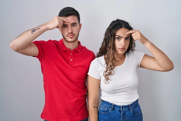Young Hispanic Couple Standing Isolated Background Pointing Unhappy Pimple Forehead — Stock Photo, Image