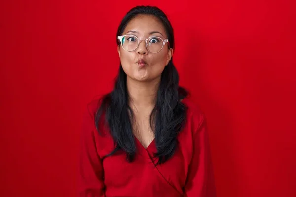 Kırmızı Arka Planda Duran Asyalı Genç Bir Kadın Dudaklarıyla Balık — Stok fotoğraf