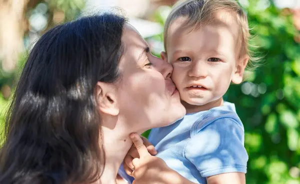 Mother and son smiling confident kissing at park
