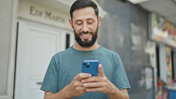 Молодий Іспаномовний Чоловік Використовує Смартфон Навушники Посміхаючись Вулиці — стокове фото