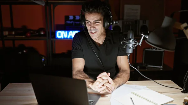 Young hispanic man speaking in a radio show at radio studio