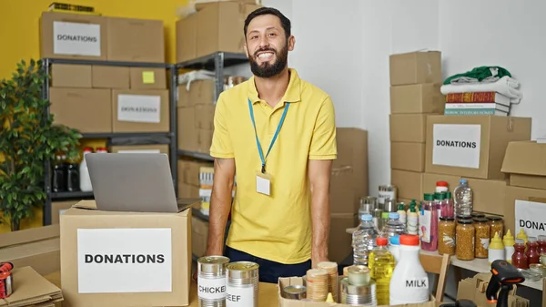 Young hispanic man volunteer smiling confident standing at charity center