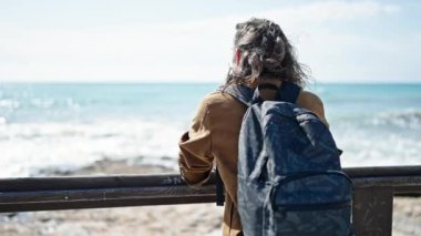 Sırt çantalı genç İspanyol turist deniz kenarında dikiliyor.