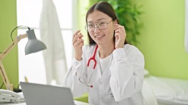 Genç Çinli kadın doktor klinikte dizüstü bilgisayar kullanıyor.