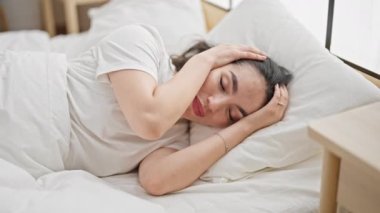 Young beautiful hispanic woman covering ears for noise at bedroom