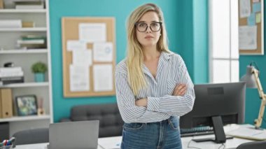 Genç sarışın iş kadını ofiste kendine güvenen gülümsüyor.