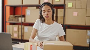Afrika kökenli Amerikalı kadın ekommerce işçisi müzik dinliyor ofiste kağıtları paketliyor