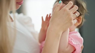 Anne ve kızı evde birbirlerine gülümsüyorlar.