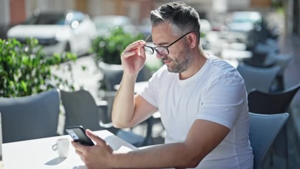 Grijsharige Man Met Smartphone Die Zijn Bril Afdoet Het Terras — Stockvideo