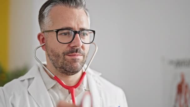 Gråhårig Man Läkare Står Med Allvarliga Uttryck Undersöka Patienten Kliniken — Stockvideo