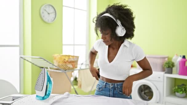 Mujer Afroamericana Escuchando Música Planchando Ropa Lavandería — Vídeos de Stock