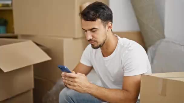 Νεαρός Ισπανόφωνος Άνδρας Χρησιμοποιώντας Smartphone Κάθεται Στον Καναπέ Νικητή Χειρονομία — Αρχείο Βίντεο