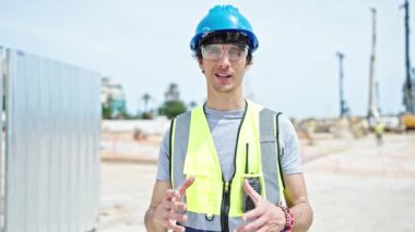 Genç İspanyol mimar inşaat alanında kendinden emin bir şekilde gülümsüyor.