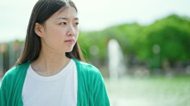 Parkta yüzünde ciddi bir ifade olan genç Çinli kadın.