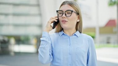 Genç sarışın iş kadını akıllı telefondan konuşuyor. Sokakta nöbet tutuyor.
