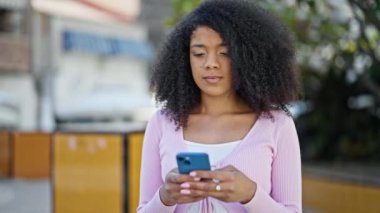Afro-Amerikalı kadın parkta akıllı telefon kullanıyor.