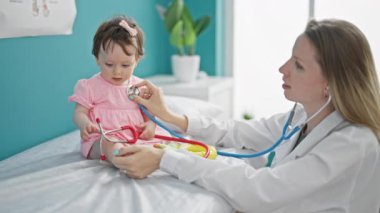 Anne ve kız çocuk doktoru klinikte bebek sandığını inceliyor.
