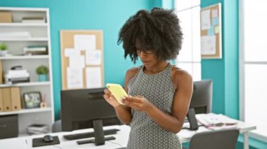 Afrika kökenli Amerikalı iş kadını akıllı telefon kullanarak ofiste baş parmak hareketi yapıyor.