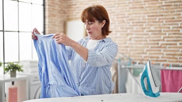 中世の女性アイロン服を保持シャツ見て動揺でランドリールーム — ストック動画