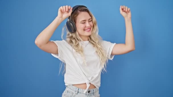 Mladá Blondýna Žena Poslouchá Hudbu Tanec Přes Izolované Modré Pozadí — Stock video