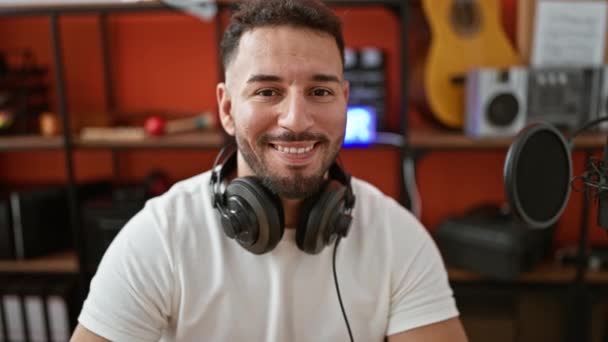 年轻的阿拉伯男子音乐家 戴着耳机 在音乐工作室里微笑 — 图库视频影像